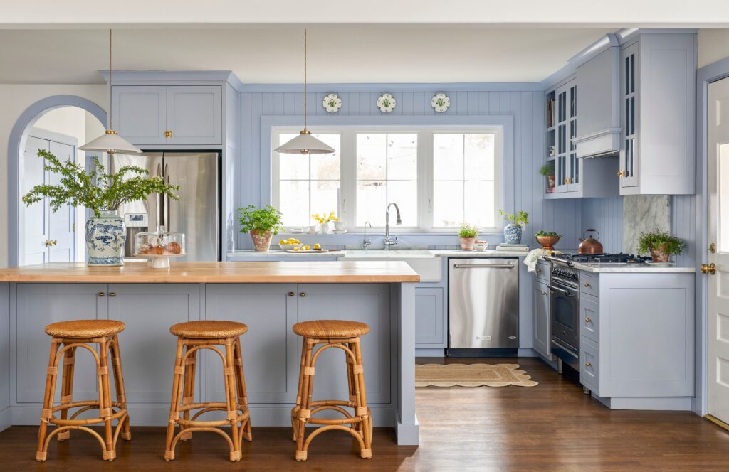 Cozy kitchen with pastel blue cabinets, wood countertops, wicker stools, and vintage farmhouse décor
