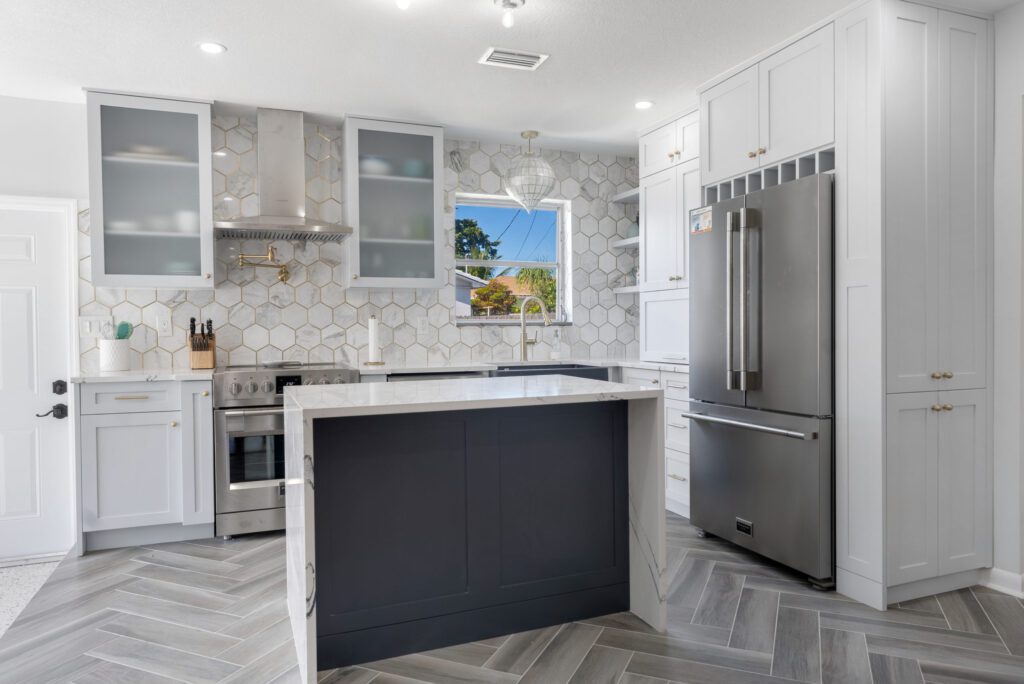 Stylish kitchen with white and navy cabinets, hexagonal tile backsplash, and stainless steel appliances