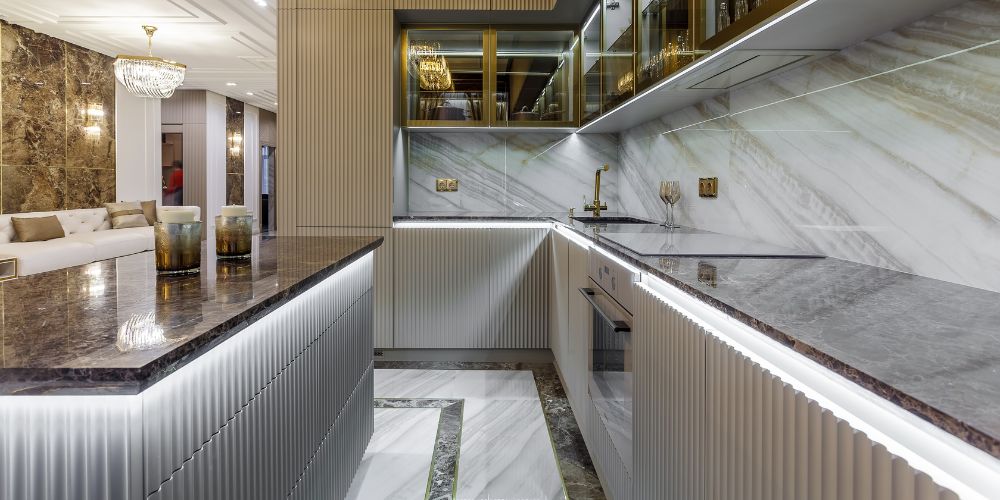 Luxurious kitchen with fluted cabinets, dark marble countertops, marble backsplash, and LED strip lighting