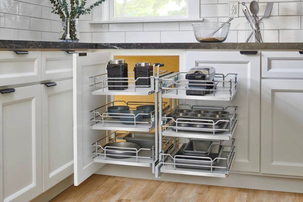 A modern white kitchen featuring a blind corner cabinet with a pull-out organizer system filled with cookware and kitchen appliances.