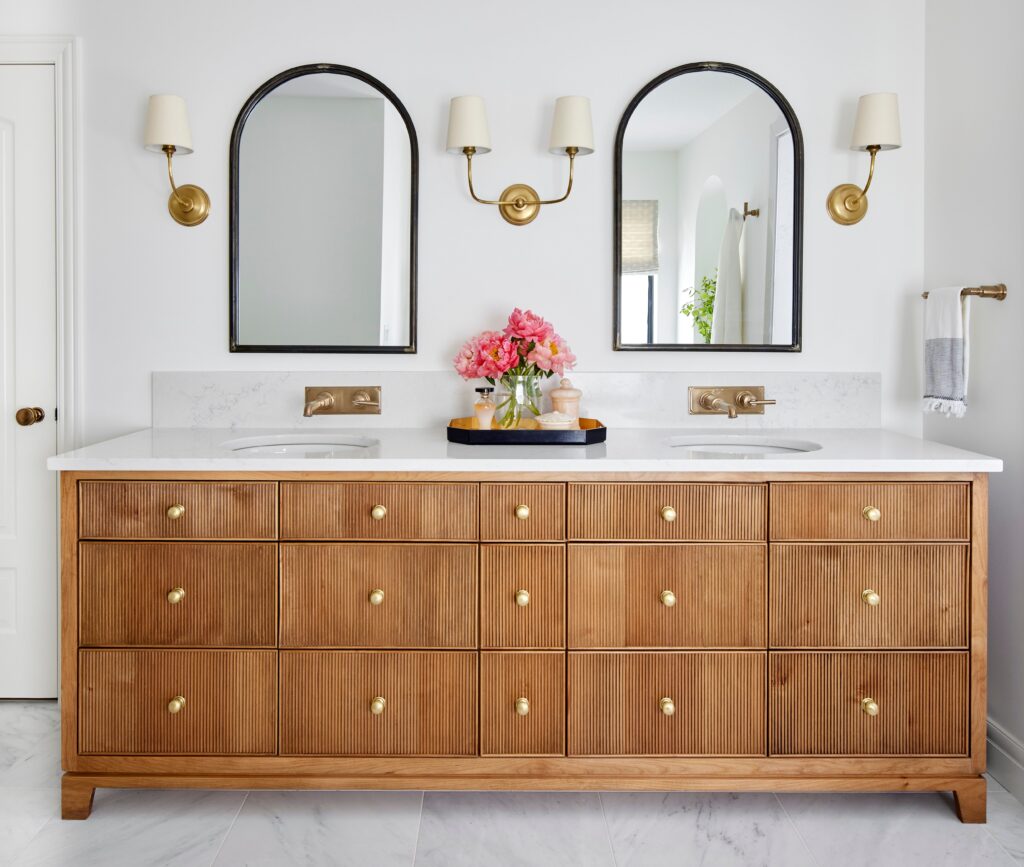 Double sink bathroom vanity with wood drawers and brass fixtures