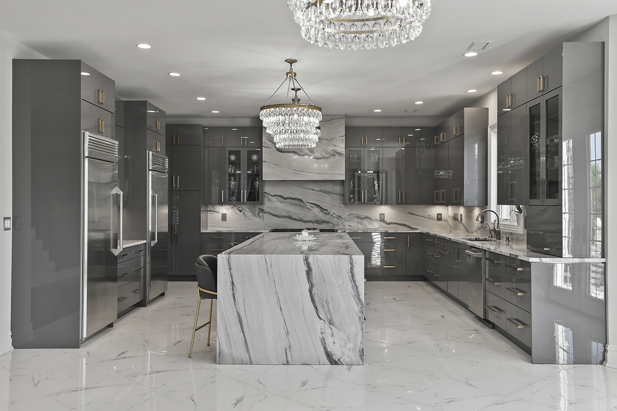 Modern kitchen featuring glossy gray cabinets, dramatic marble island, and crystal chandeliers