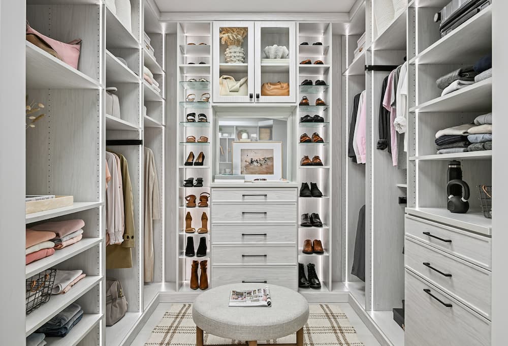 Modern white walk-in closet with built-in drawers, shelves, hanging space, and illuminated shoe racks