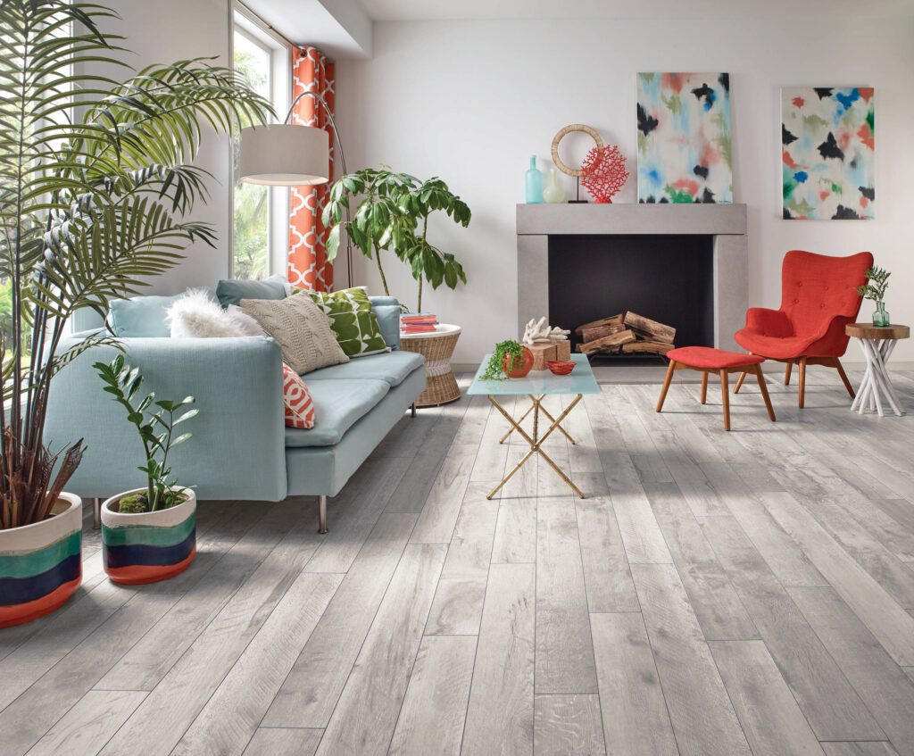 A colorful living room featuring light gray wood flooring, vibrant furniture, and plenty of natural light.