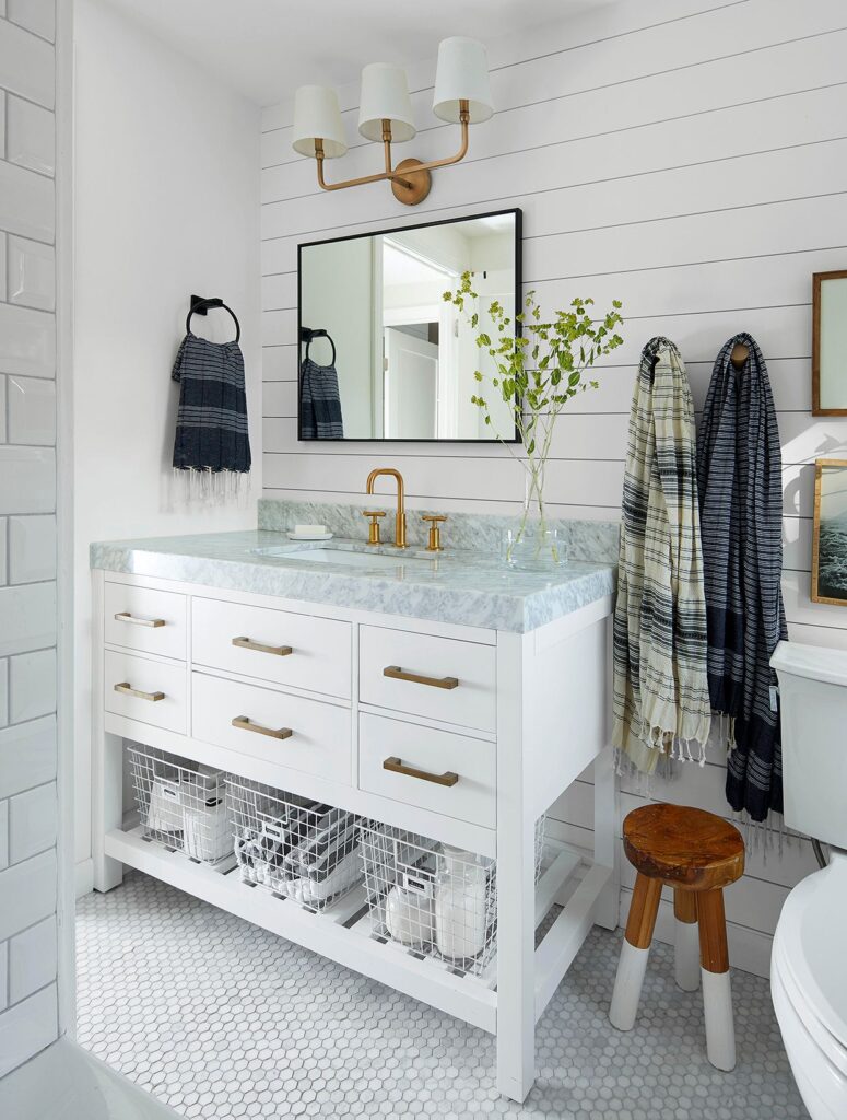 White bathroom vanity with marble countertop and gold fixtures