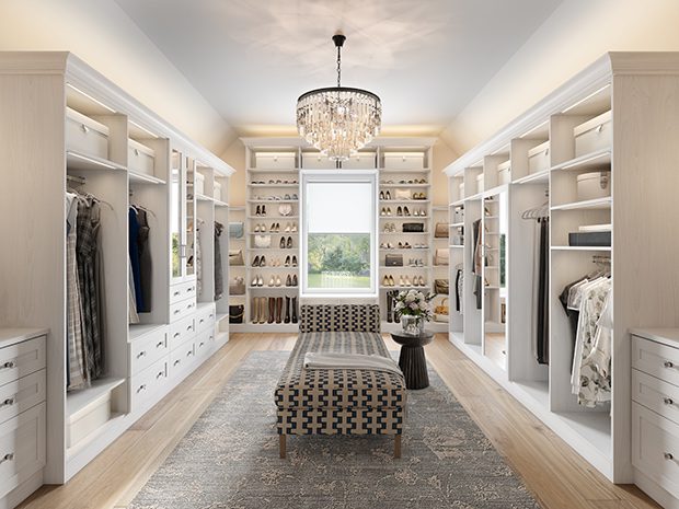 Spacious white walk-in closet with custom shelving, a central seating area, and a crystal chandelier