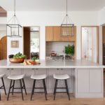 Bright kitchen with light wood cabinets, marble island, and modern pendant lights