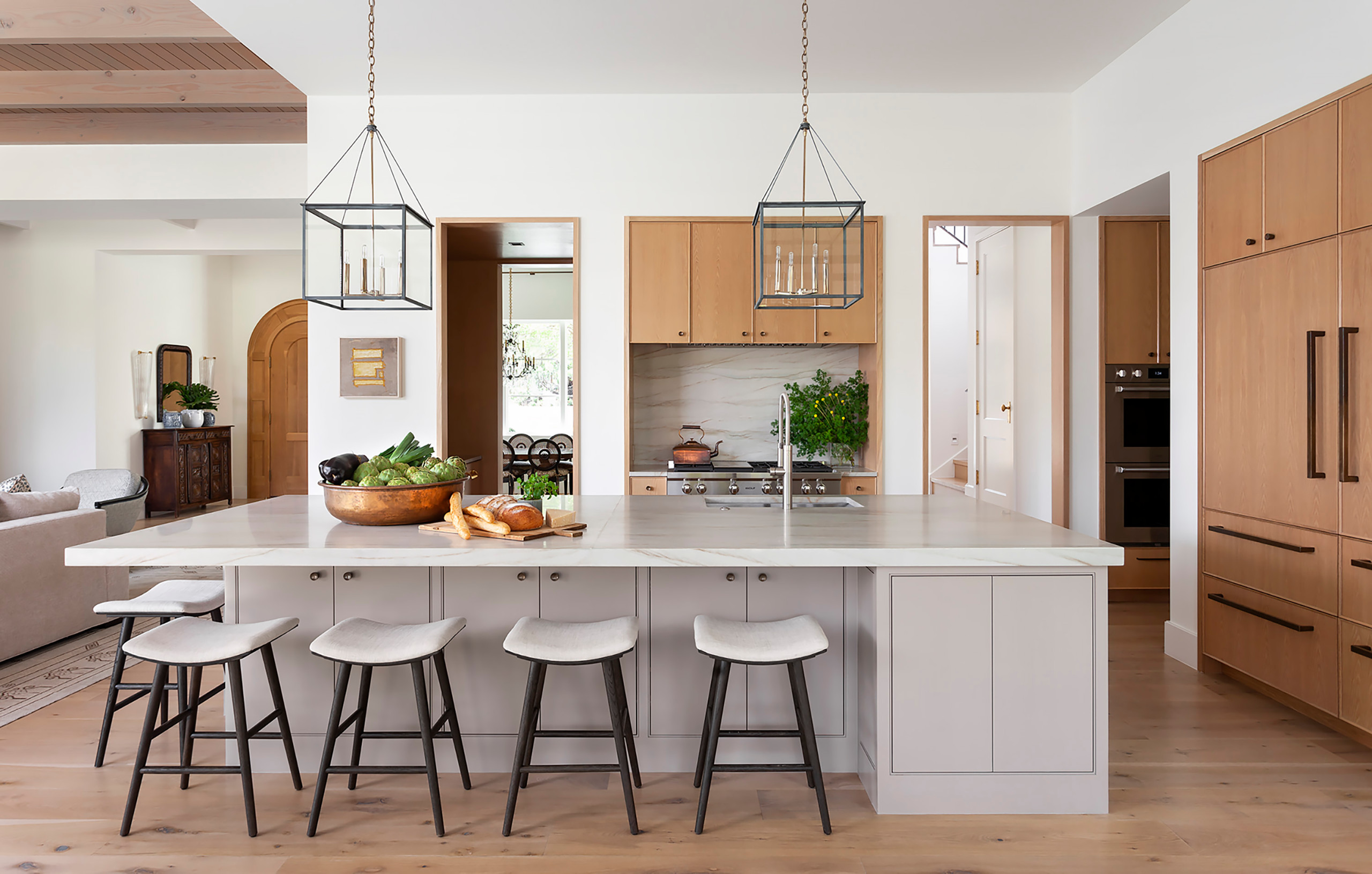 Bright kitchen with light wood cabinets, marble island, and modern pendant lights