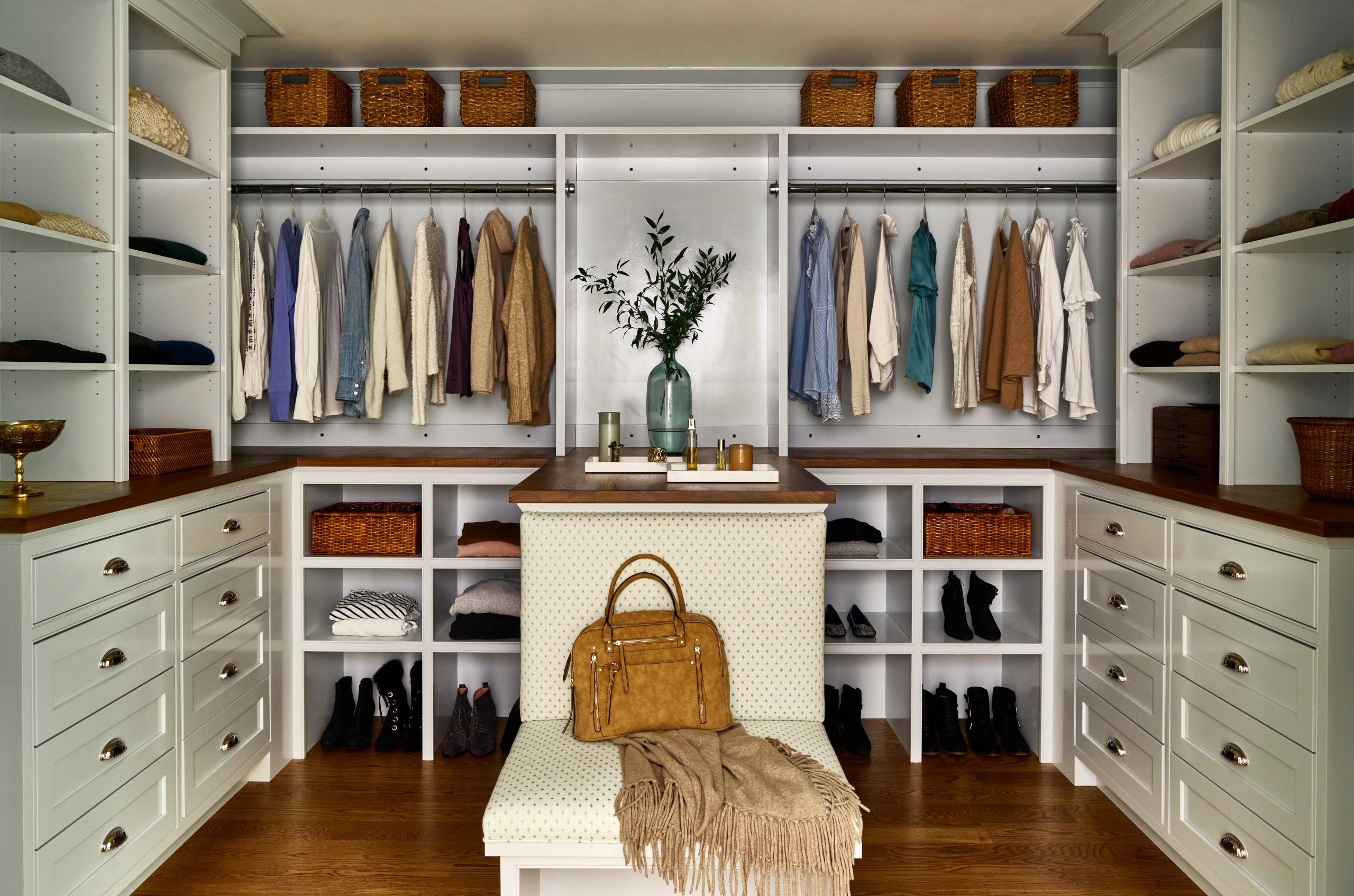 Spacious walk-in closet with custom cabinetry, seating, and organized storage