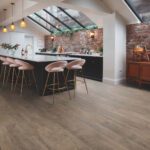 Industrial-style kitchen with exposed brick wall, large island, and wooden flooring.