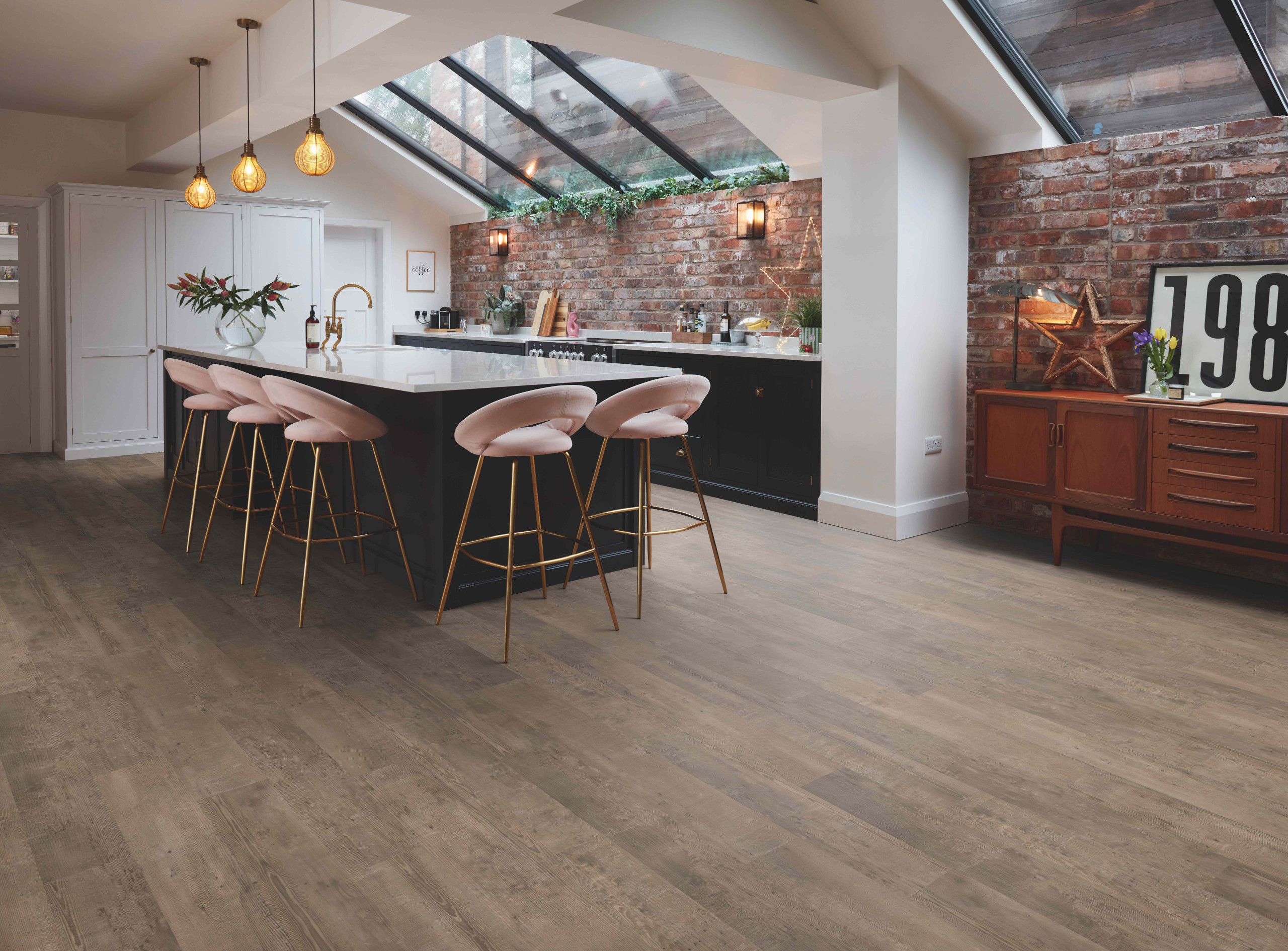 Industrial-style kitchen with exposed brick wall, large island, and wooden flooring.