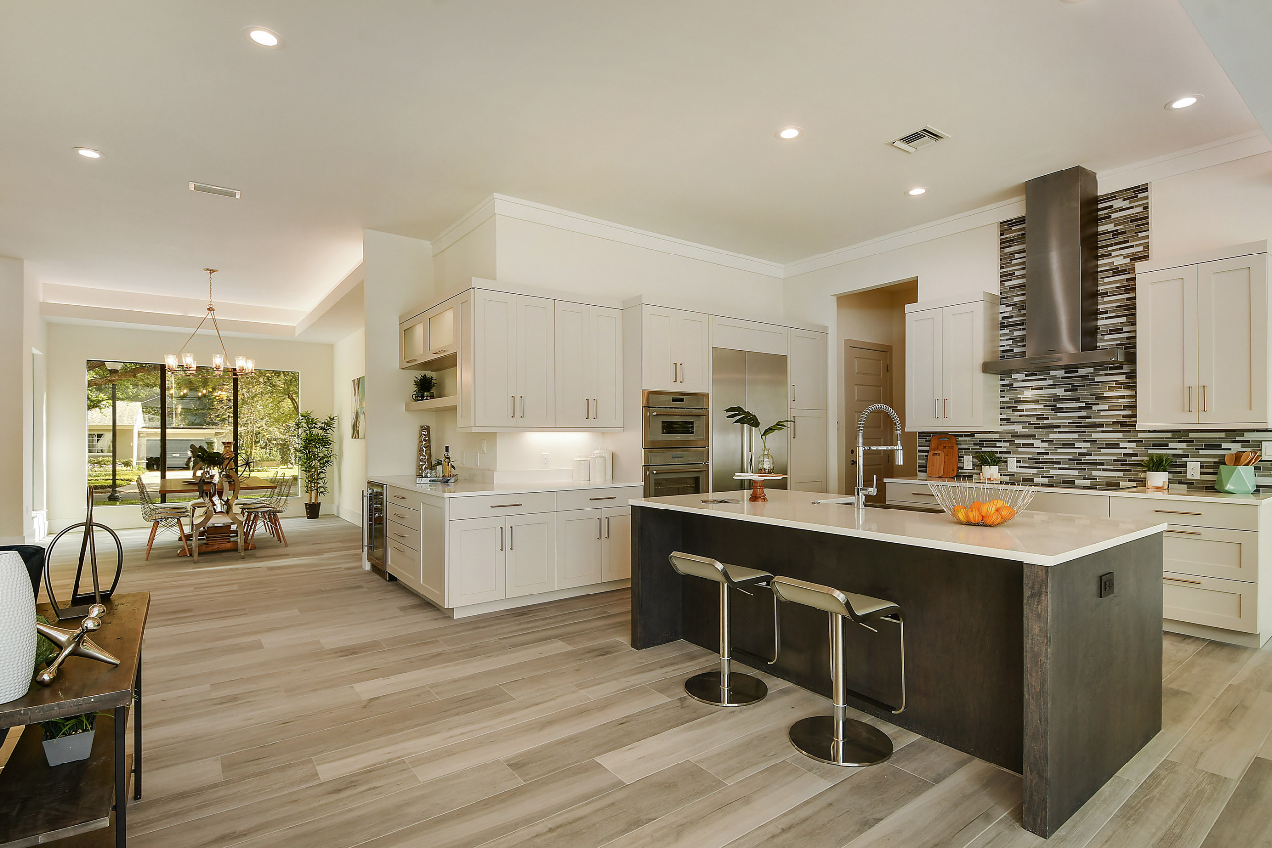 Modern kitchen with white cabinets, sleek island, and mosaic backsplash