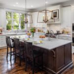 Traditional white kitchen with large island, dark wood accents, and pendant lighting