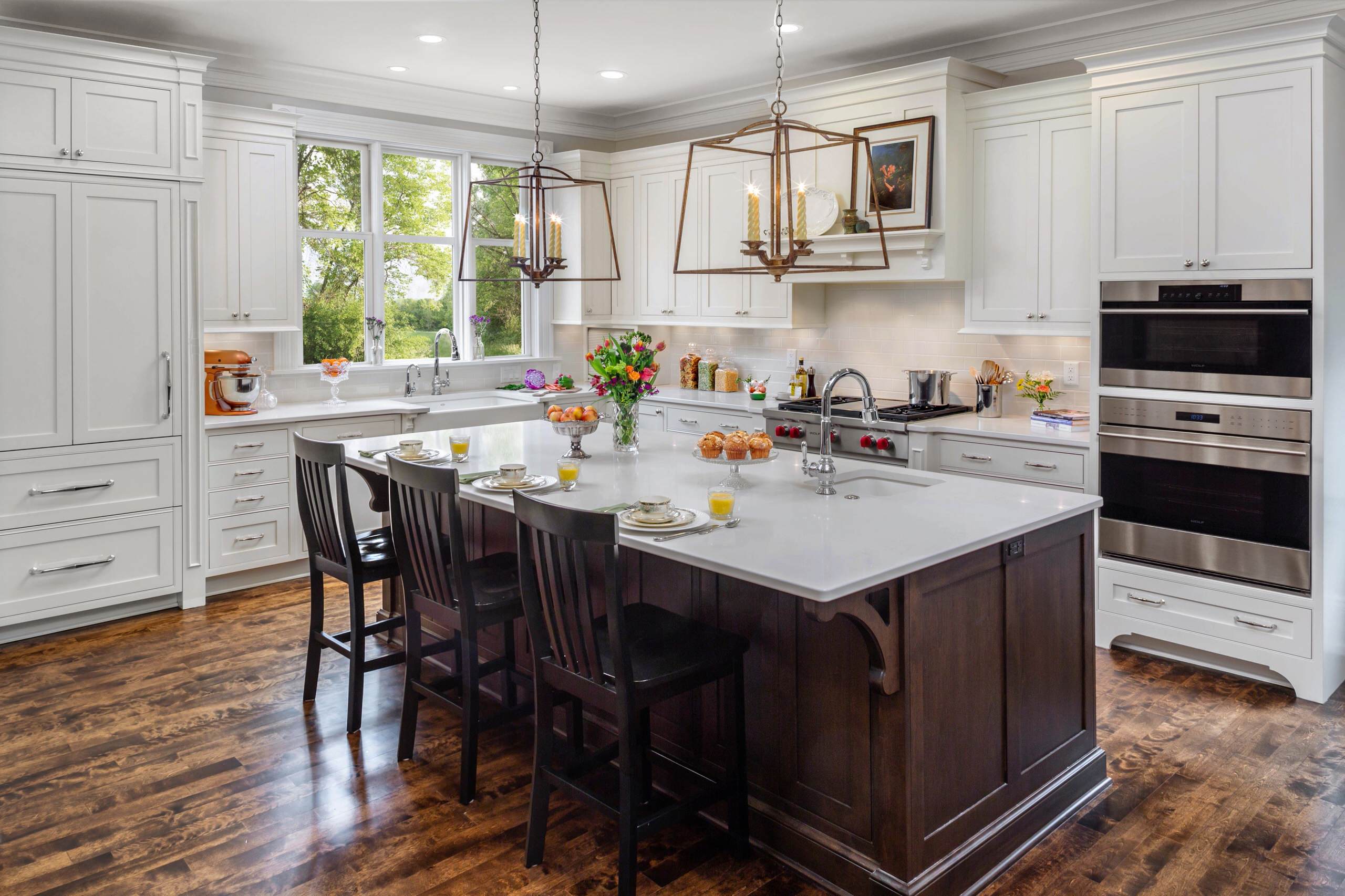Traditional white kitchen with large island, dark wood accents, and pendant lighting