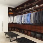 Luxury walk-in closet with dark wood cabinetry, organized clothing, and modern benches