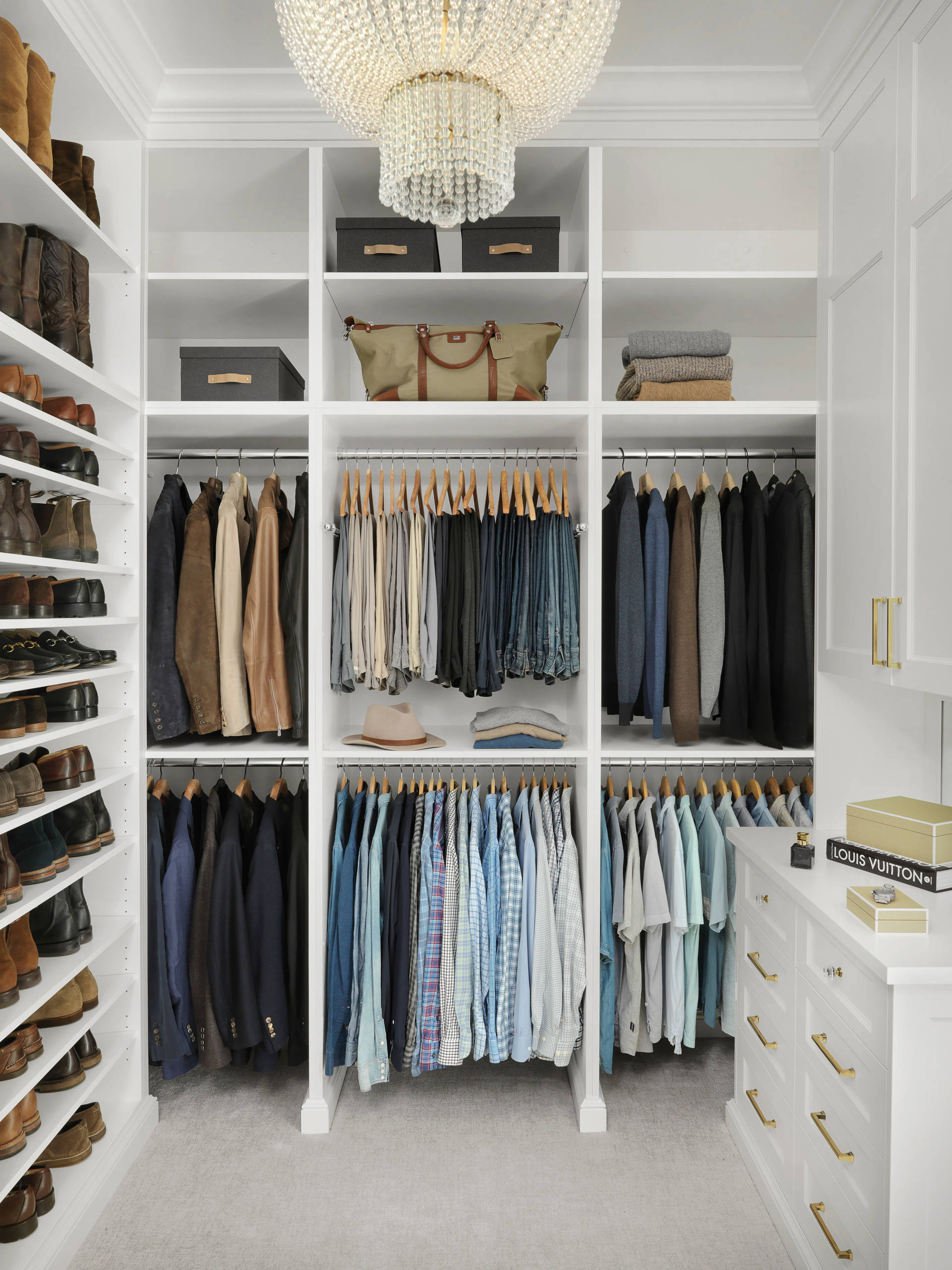 Modern walk-in closet with white cabinetry and crystal chandelier