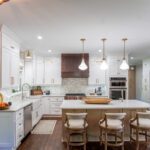 Transitional kitchen with white cabinets, wood range hood, and central island