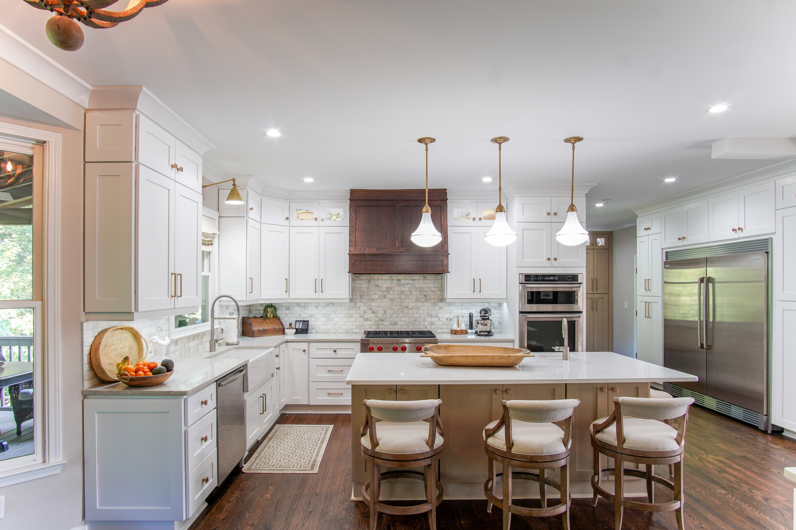 Transitional kitchen with white cabinets, wood range hood, and central island