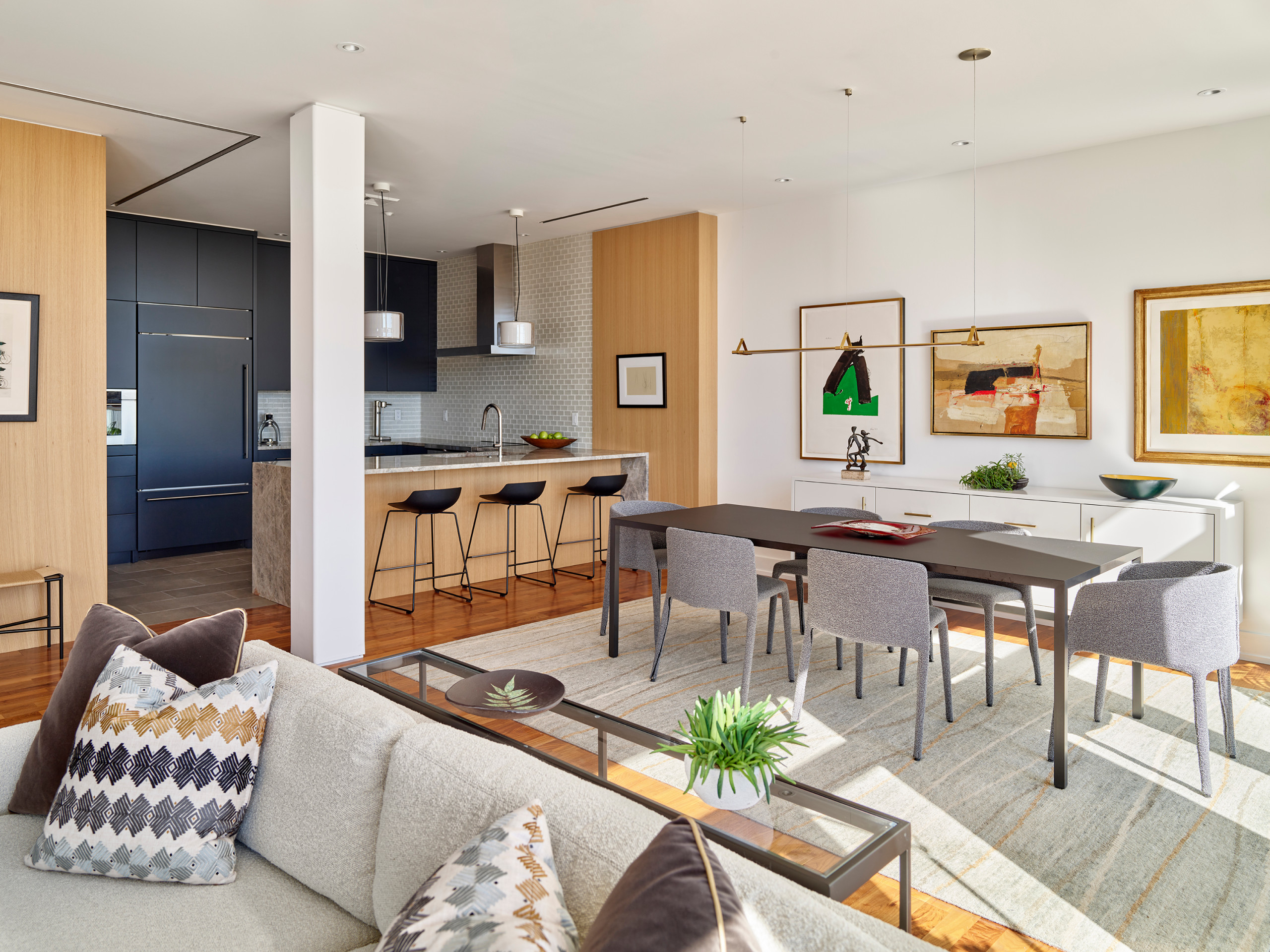 Modern open-concept kitchen and dining area with wood accents, black cabinetry, and contemporary artwork.